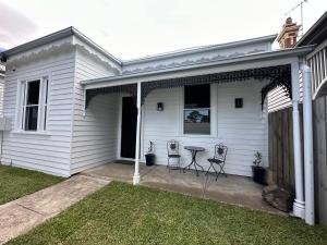 een wit huis met twee stoelen en een tafel bij Garden Cottage in Geelong