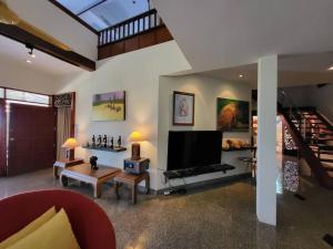 a living room with a flat screen tv and a staircase at Bougainvillea Terrace House in Kata Beach