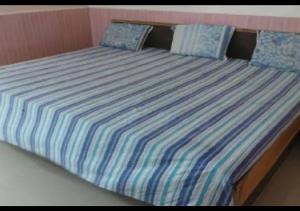 a bed with striped sheets and blue pillows on it at Hotel M. S. Palace By WB Inn in Agra