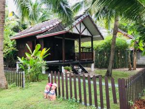 dos niños parados detrás de una valla delante de una casa en First Villa Beach Resort, en Baan Tai