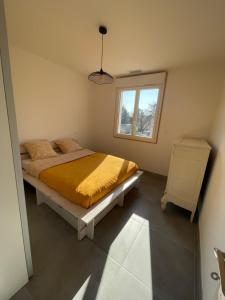 - une chambre avec un lit doté d'une couette jaune et d'une fenêtre dans l'établissement Chez Jo’, à Vézénobres