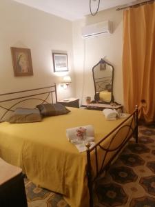 Un dormitorio con una gran cama amarilla con espejo en Dal corso al mare, en Spadafora