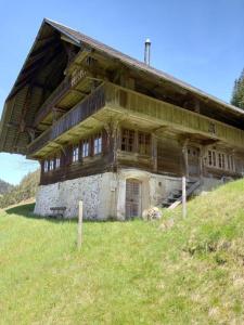 una vieja casa de madera en una colina con hierba en Antikes Ferienhaus, en Trub