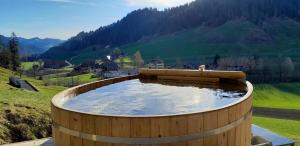 eine große Holzbadewanne mit Wasser auf einem Hügel in der Unterkunft Antikes Ferienhaus in Trub