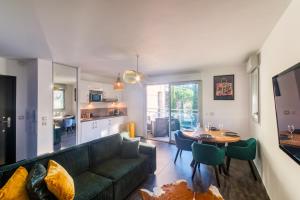 salon z zieloną kanapą i stołem w obiekcie Villa Elena - Studio proche plage avec terrasse w Cannes