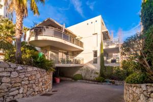 biały budynek z balkonem i palmami w obiekcie Villa Elena - Studio proche plage avec terrasse w Cannes