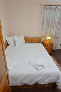 Una cama con sábanas blancas y dos servilletas. en Зелената Къща 