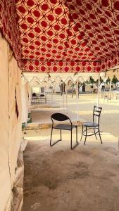 two chairs sitting under a pavilion with a table and chairs at Thar Royal Desert Camp in Sām