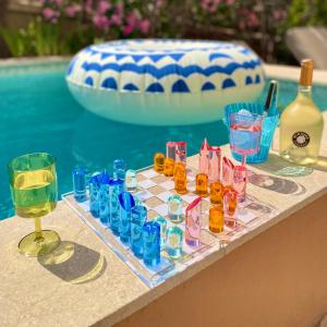 a chess board and glasses on a table next to a pool at Le Gabriel in Claviers