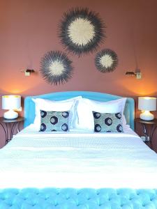 a bedroom with a blue bed with two mirrors on the wall at Le Gabriel in Claviers