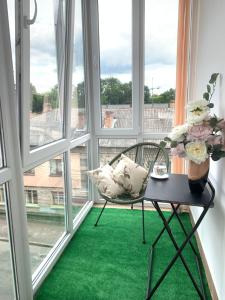 a chair sitting on a table in a room with windows at Центр (6). Поруч Став та Парк in Ternopilʼ