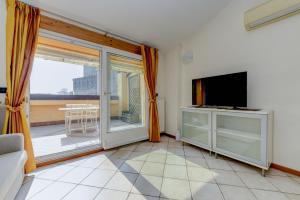 a living room with a tv and a sliding glass door at Sunset Apartment Home & Terrace in Sirmione