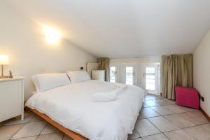 1 cama blanca grande en una habitación con ventanas en Sunset Apartment Home & Terrace, en Sirmione