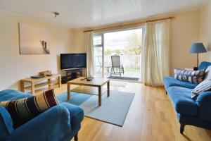ein Wohnzimmer mit einem blauen Sofa und einem TV in der Unterkunft Nyhavn Lakeside Cottage in Cirencester