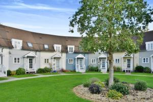 a large building with a tree in a yard at Nyhavn Lakeside Cottage in Cirencester