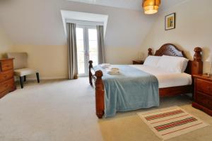 a bedroom with a bed and a chair and a window at Nyhavn Lakeside Cottage in Cirencester