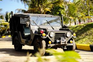 un jeep militar estacionado en una carretera con palmeras en KNN RESORT Mondulkiri en Sen Monorom