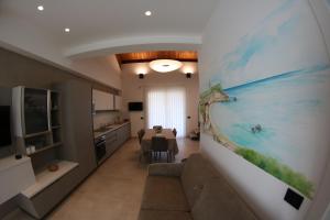 Mirko's house في ليكاتا: مطبخ وغرفة معيشة مع لوحة كبيرة على الحائط