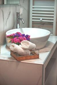 un lavabo con flores y una cesta de toallas. en CRETAN VILLA OLIVIA en Karteros