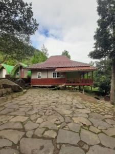 a house with a porch and a stone patio at Curug Ciherang Villa & Glamping 