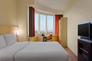 a hotel room with a bed and a large window at Ibis Yanbu in Yanbu