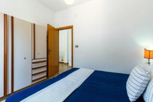 een slaapkamer met een bed met blauwe lakens en een deur bij Appartamento Vespucci Bilo - MyHo Casa in Tortoreto Lido