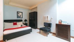 a bedroom with a bed and a chair at RedDoorz Plus at Holiday Plaza Hotel Tuguegarao City in Tuguegarao City