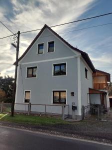 una casa blanca al lado de una calle en Ferienwohnung am Olbasee en Malschwitz