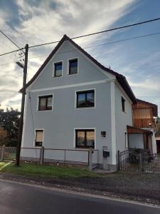 a white house on the side of a street at Ferienwohnung am Olbasee in Malschwitz