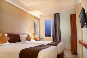 a hotel room with two beds and a window at H Boutique Hotel Jogjakarta in Yogyakarta