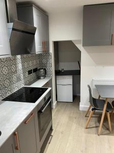 a kitchen with a stove top oven next to a table at Orchard Lane Great Glen Unique 2 bed cosy home in Great Glen