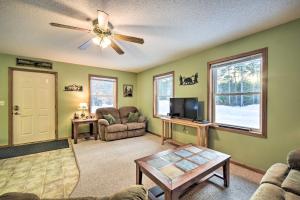 a living room with a ceiling fan and a tv at Wooded Danbury Cabin with Grill and Fire Pit! in Danbury