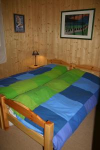 Schlafzimmer mit einem Bett mit einer grünen und blauen Bettdecke in der Unterkunft LATITUDE 47 in Châtel
