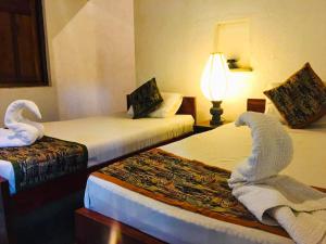 a hotel room with two beds with swans on them at Eth Mansala in Sigiriya