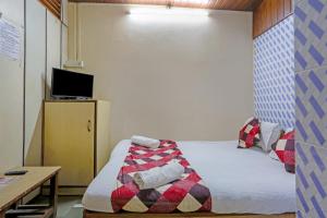 een kleine kamer met een bed met een deken erop bij Terminus Hotel Bandra in Mumbai
