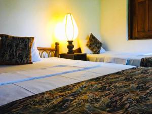 a hotel room with two beds and a lamp at Eth Mansala in Sigiriya