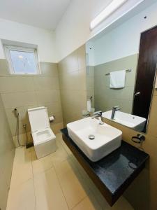 La salle de bains est pourvue d'un lavabo, de toilettes et d'un miroir. dans l'établissement Luxe Highway Residencies, à Kottawa