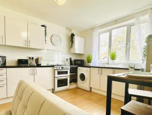 a kitchen with white cabinets and a table with a couch at Beautiful 3-Bed Apartment with Driveway Parking in Nottingham