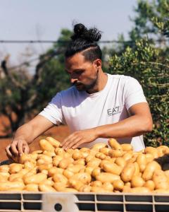 Un uomo in piedi accanto a una scatola di patate di Agriturismo Paradiso a Parabita