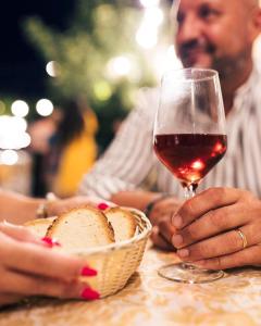un uomo seduto a un tavolo con un bicchiere di vino di Agriturismo Paradiso a Parabita