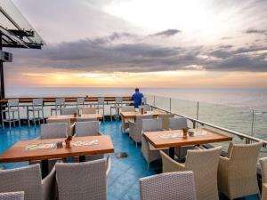 un hombre parado en el balcón de un restaurante con vistas al océano en The Ocean Colombo, en Colombo