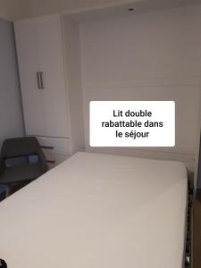 Cette chambre comprend un lit blanc avec un panneau. dans l'établissement LA PLAGE, à Berck-sur-Mer