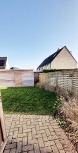 a backyard with a brick walkway and a fence at Salty - Vakantiehuisje op de grens van Bredene-De Haan in Bredene