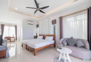 a bedroom with a bed and a couch and a ceiling fan at Angel Stay Pool Villa Pranburi บ้านพักปราณบุรี พูลวิลล่าปราณบุรี ติดทะเล in Ban Pru Yai +62 photos