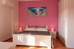 a bedroom with a white bed and a pink wall at casavacanzabordonaro in Palermo