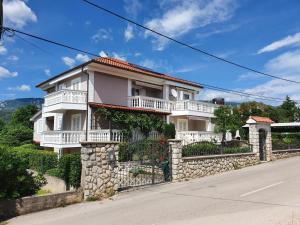 a large white house with a stone wall at Villa Karla in Jadranovo