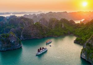dos barcos en un cuerpo de agua con montañas en Arcady Boutique Cruise en Ha Long