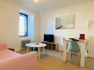 uma sala de estar com uma mesa e cadeiras e uma televisão em LE CLOS RUTHÈNE em Rodez