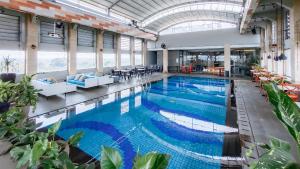 a large pool with blue water in a building at The Excelton Hotel in Palembang