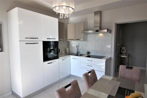 a kitchen with white cabinets and a table with chairs at Apartments Marina in Rabac